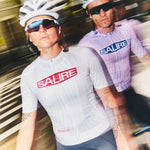 Two cyclists wearing Salire jerseys riding on a road with a blurred background