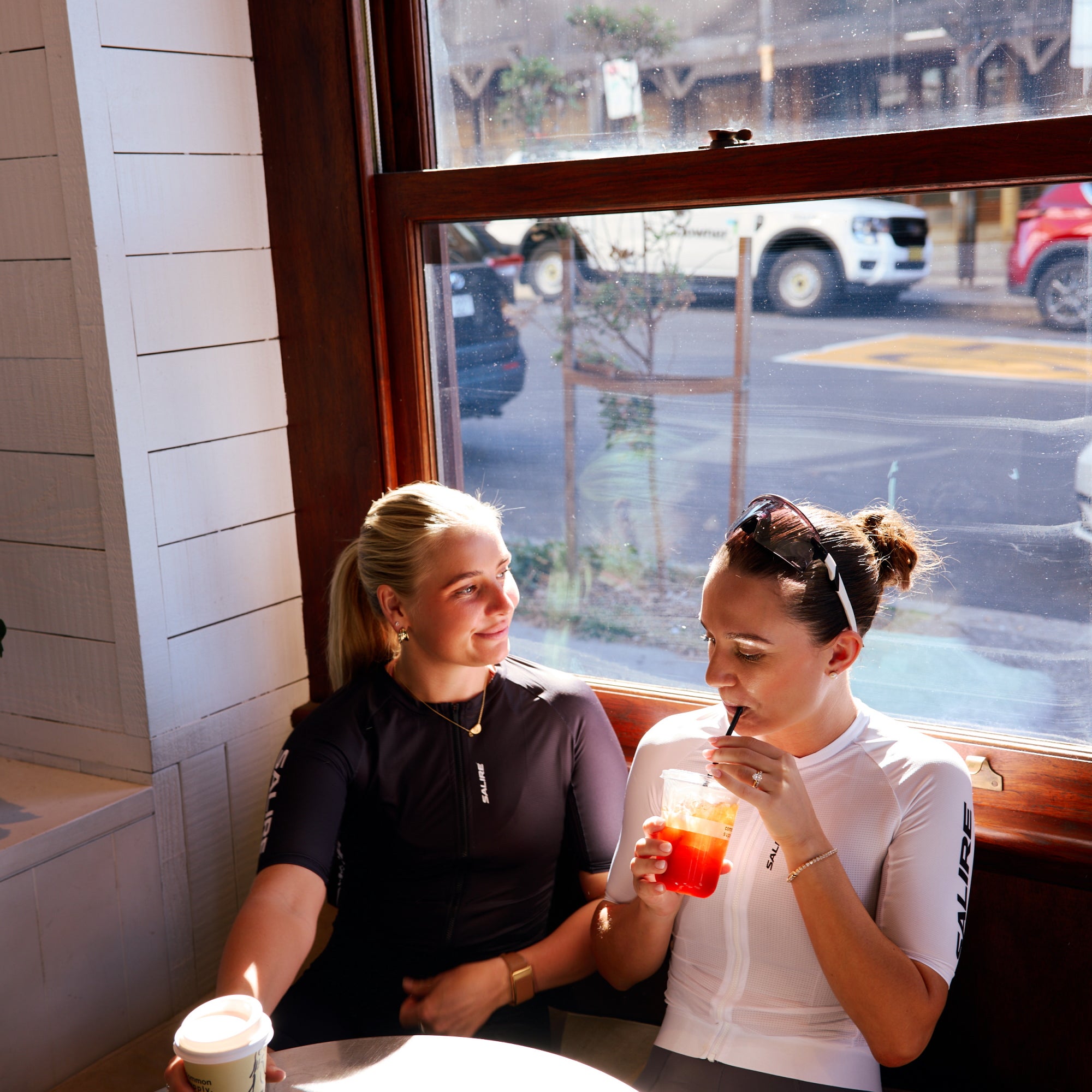 Two cyclists wearing Salire kits sitting at a table in a cafe